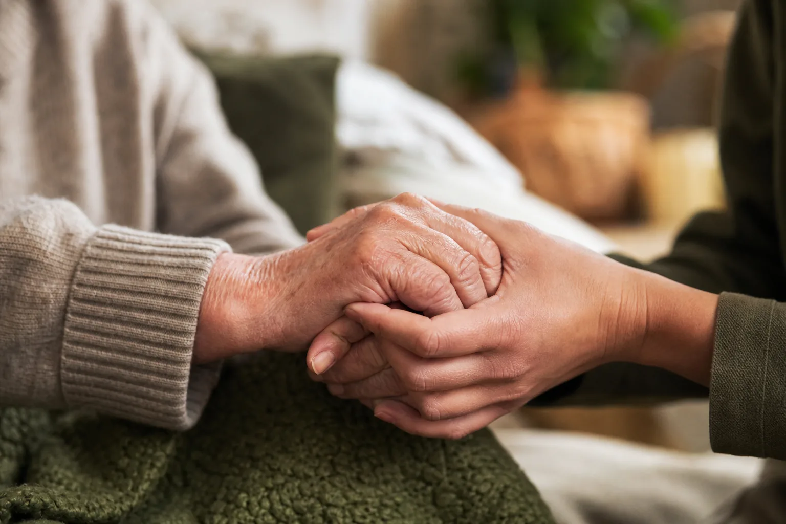 Main d'un soignant tenant avec douceur la main d'une personne âgée